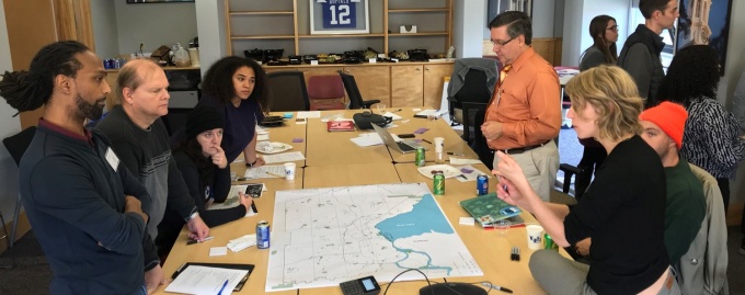 A group of urban planning faculty and students and community members from Buffalo stand over a map discussing climate resilience strategies. 