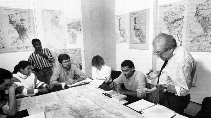 Ibrahim "Jimi" Jammal, one of the school's first faculty members in urban planning, looks over maps with his students in Hayes Hall. 
