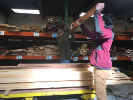 students hold a piece of lumber over their heads as they work on the transformable shells project in the Shop. 