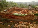 Mortar is kept moist during wall construction by placing banana leaves and other materials on the top course of bricks.