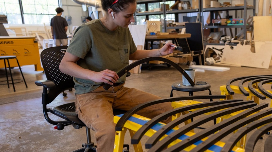 Student working on piece of furniture in fabrication workshop. 