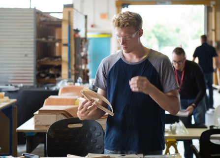 Students wearing safety goggles while working in wood shop. 