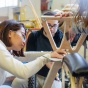 Students working together, wearing protective goggles, sanding a large wood project. 