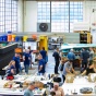 Wide view of the main open workshop space with students and teachers engaging in making ceramics. 