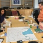 A group of urban planning faculty and students and community members from Buffalo stand over a map discussing climate resilience strategies. 