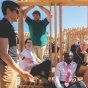 students sitting on their design build project, a wooden structure. 