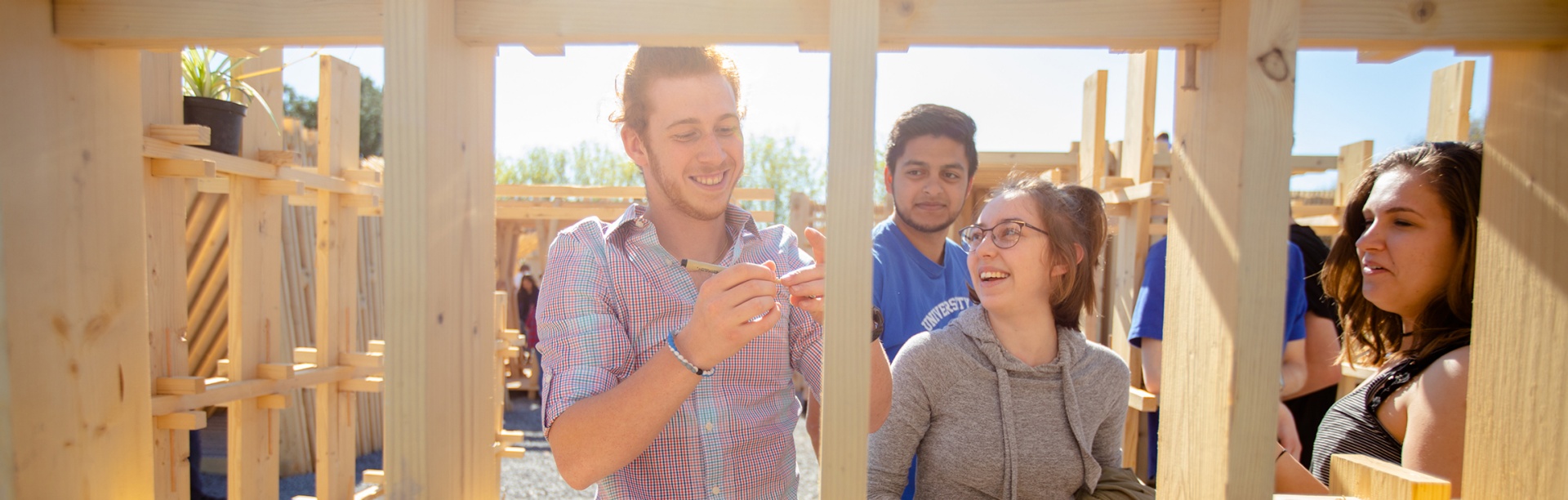 Students gather outdoors around one of their outdoor project installations. 