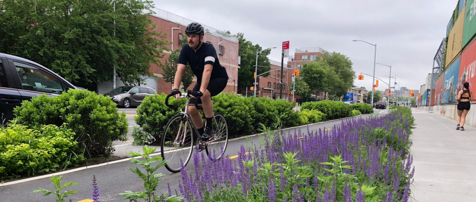 Bicycle rider on flower lines sidewalk in urban area. 