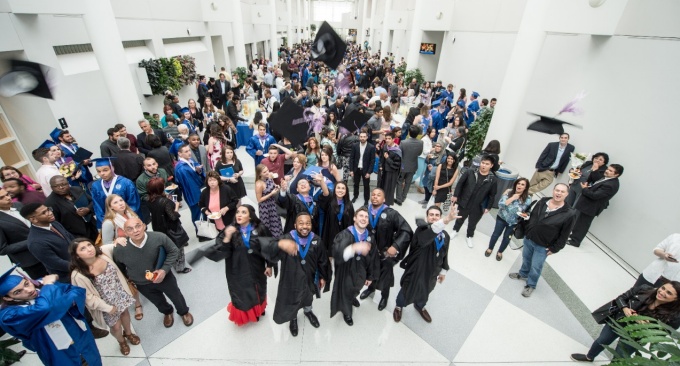 Commencement 2017 - graduates in the atrium of the Center for the Arts toss their caps in to the air in celebration. 