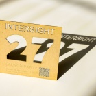 Intersight 27 etched out of a wooden square, highlighting the shadows of the cutout. 