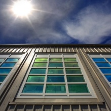 Image of building with glass panels radiating sunlight. 