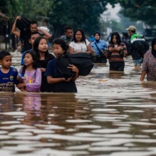Families in Indonesia walk through flooded streets. 