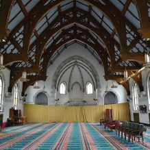 Interior view of the Jami Masjid show the replaced windows and Turkish carpeting for Islamic prayer. The murals have been painted sky blue and the walls are adorned with Arabic calligraphy. 