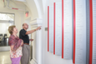 Beverly Foit Albert-Cox (MArch '75) and Joseph D. Cox (MA '96) stand in front of the donor wall on the fourth floor of Hayes Hall. The names of 250 donors to the renovation effort are listed here.