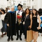 Miguel Guitart, Mayank Sharma, Mayank's mother, and fellow UB alumn Behnoush Nikparvar pose in the lobby of UB's Center for the Arts following the graduation ceremony. 